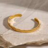 Brazalete Abierto Martillado Acero Inoxidable y enchapado en oro de 18k hermoso